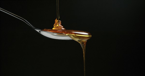 Honey Flowing against Black Background