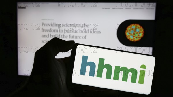 Stuttgart, Germany, 11-02-2023: Person holding cellphone with logo of American foundation Howard Hughes Medical Institute (HHMI) in front of webpage. Focus on phone display, Europe