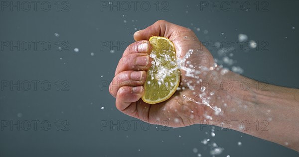 Hand of Man Squeezing Lemon, citrus limonum against Black Background