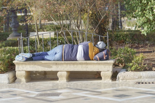Homeless man sleeping on a park bench