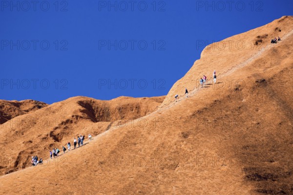 Uluru, Australia, July 4, 2015: Climbers ascend Uluru against the wishes of the Aborginal land owners, Oceania