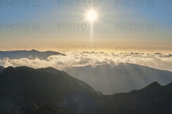 Aerial drone view of mountains over clouds near Pico Ruivo on sunset. Madeira island, Portugal, Europe