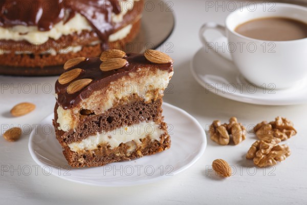Homemade chocolate cake with milk cream, caramel and almonds on white wooden background. cup of coffee, close up