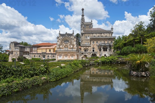 Historisches Schloss mit reflektiertem Bild im See, umgeben von Bäumen und bewölktem Himmel, Palácio Hotel do Buçaco, Mata Nacional do Buçaco, National-Wald von Bussaco, Bucaco, Mealhada, Beira Litoral, Portugal, Europe