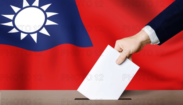 Taiwan presidential election. Hand holding ballot in ballot box with Taiwan flag in background