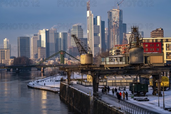 The skyline of Frankfurt am Main, skyscrapers of the banking district, historic harbour cranes at the Wesel shipyard, wintry morning, Hesse, Germany, Europe
