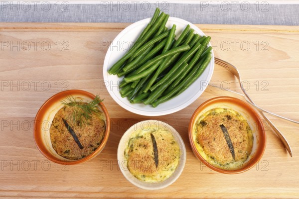 Swabian cuisine, oven-baked pike-perch with princess beans and lemon sauce, fish dish, pike-perch fillet, green beans, dill, starter, from the oven, ramekins, soufflé moulds, served on a wooden board, traditional cuisine reinterpreted, food photography, studio, Germany, Europe