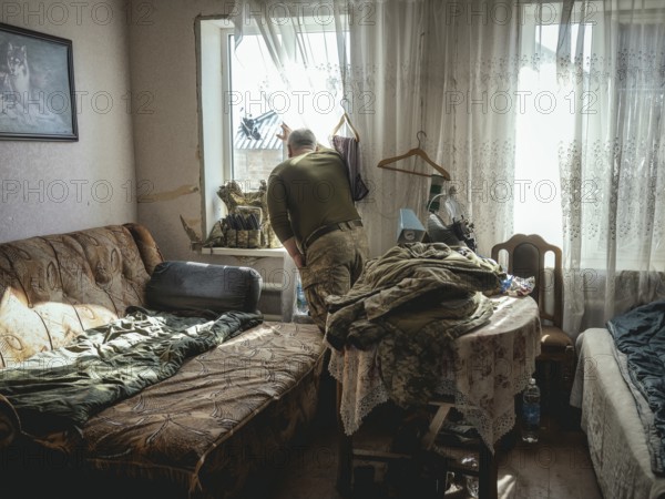 Gennady, 48 years old, stationed in Kupyansk, looking out of the window of the house where his unit has taken up position, Kupyansk is under Russian attack, Kupyansk, Kharkiv Oblast, Ukraine, Europe