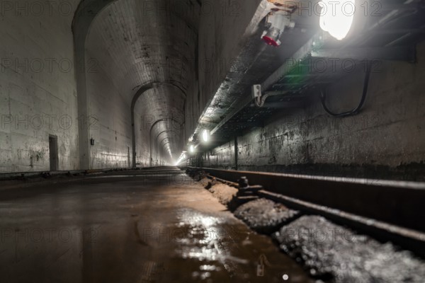 Deep tunnel with wet concrete walls and light at the end, industrial ambience, Rappbodetalsperre, Harz, Germany, Europe