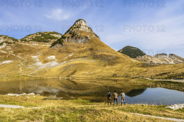 The Austrian alphorn trio Klangholz plays the alphorn at Lake Augstsee on Mount Loser. Mount Atterkogel in the background. Autumn, good weather, blue sky. Reflection. Altaussee, Bad Aussee, Ausseer Land, Totes Gebirge, Styria, Upper Austria, Austria, Europe