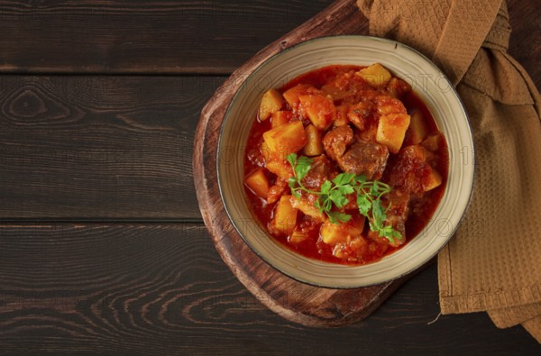 Stew with potatoes, in tomato sauce, with spices and herbs, close-up, no people, on a black background