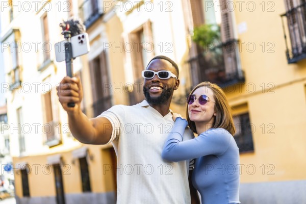 Modern multi-ethnic couple influencer recording a video vlog with smartphone in the city for online streaming apps