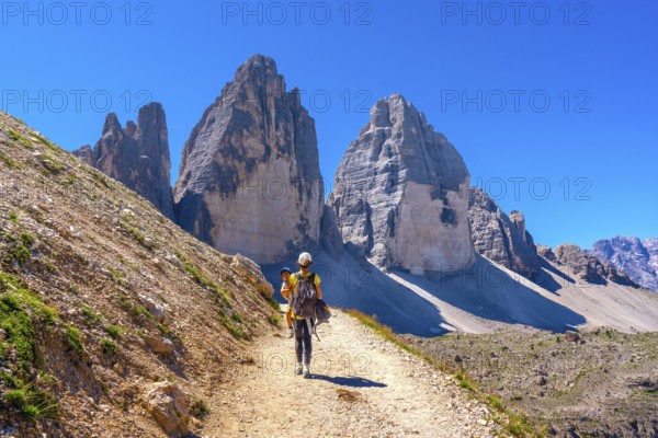 Tourists walking on a mountain path near tre cime di lavaredo, dolomites, a famous landmark in italy