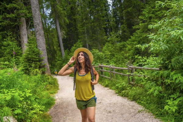 Female tourist enjoying a walk along a forest trail near lake carezza in the italian dolomites during summer