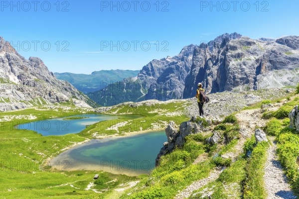 Hiker enjoying the breathtaking view of the tre cime di lavaredo peaks and the turquoise alpine lakes in the italian dolomites during a sunny summer day. Laghi dei Piani