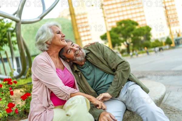 Mature couple sitting together in an urban bench contemplating the city views from the square