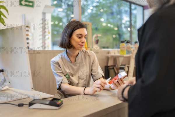 Young beauty female pharmacist attending a client in the store