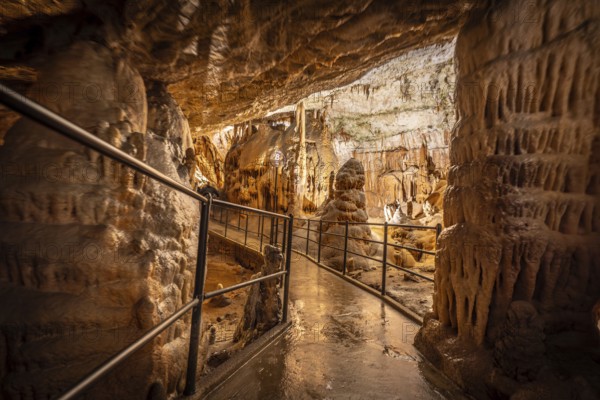Tourists enjoying a guided tour walking on the footpath inside the famous postojna cave, a natural wonder in slovenia