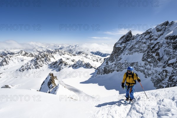 Mountaineer with ice axe and crampons, ascent through steep snowfield to Piz Kesch or Piz d'Es-cha in winter, view of mountain panorama with Vadret da Porchabella glacier, Albula Alps, Rhaetian Alps, Grisons, Eastern Switzerland, Switzerland, Europe