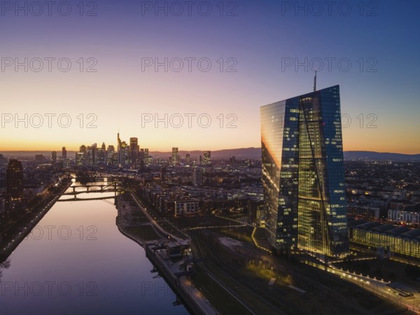 The lights in the offices of the European Central Bank (ECB) and the Frankfurt skyline glow in the evening after sunset. (Aerial view with a drone), Osthafen, Frankfurt am Main, Hesse, Germany, Europe