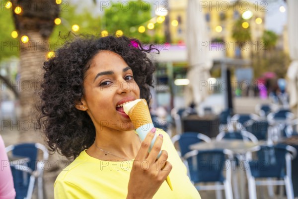 Close-up portrait of a latin woman biting an ice cream cone in the city