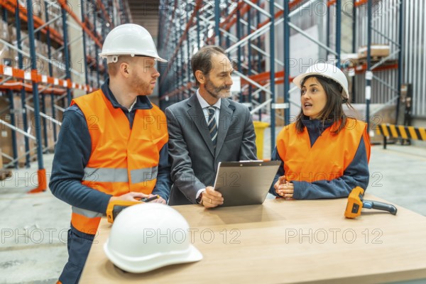 Warehouse workers and manager discussing logistics using a clipboard in a large distribution center
