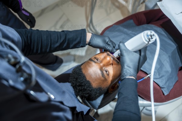 Dentist uses a professional teeth whitening lamp, enhancing a patient's smile in a state of the art dental clinic