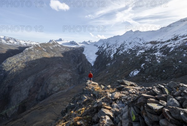 Mountaineer standing on a rock, surrounded by an impressive mountain landscape with snow-covered peaks in autumn View of Gurgler Ferner with summit Hochwilde and Falschungsspitze, Ötztal Alps, Tyrol, Austria, Europe