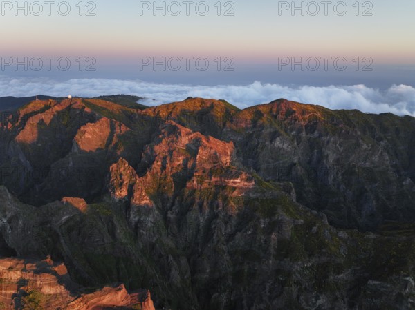 Aerial drone view of Pico do Arieiro and mountains over clouds on sunset. Above Pico Ruivo, Madeira island, Portugal, Europe
