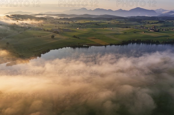 Aerial view of a lake in front of mountains in the morning light, fog, autumn, Riegsee, view of Benediktenwand and Jochberg, Alpine foothills, Upper Bavaria, Bavaria, Germany, Europe