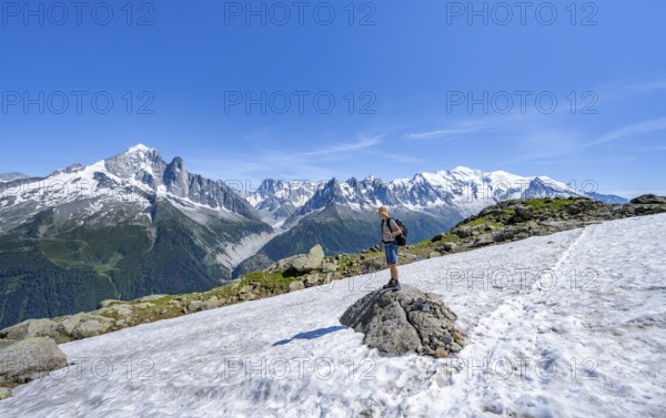 Mountaineer on a hiking trail in front of a mountain landscape, view of mountain peaks Aiguille Verte, Grandes Jorasses and Mont Blanc of the Mont Blanc massif, Aiguilles Rouges, Chamonix-Mont-Blanc, Haute-Savoie, France, Europe