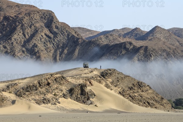 Safari vehicle on a hill in the Hoanib dry river, coastal fog, Kaokoveld, Kunene Region, Namibia, Africa