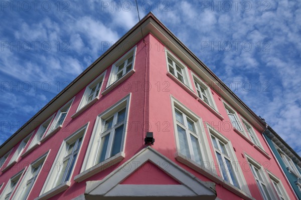 Historic building with pink facade and white window frames under a blue sky with light clouds, Bergen, Vestland, Norway, Europe