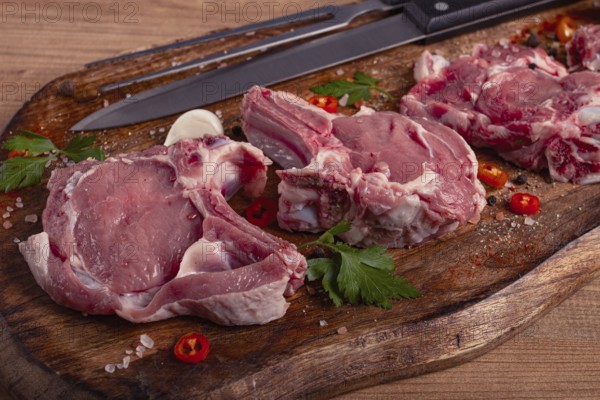 Raw calf meat, meat on the bone, meat for barbecue, cutting board, with spices and herbs, top view