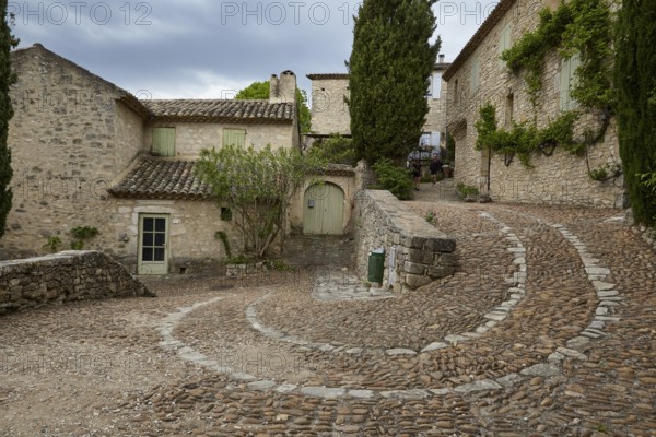 Winding path along old houses up a slope through La Roque-sur-Cèze, Département Gard, Occitania region, France, Europe