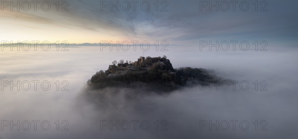 Aerial panorama of the Hegau volcano Hohentwiel with the upper fortress ruins in front of sunrise, rising out of the fog in an inversion weather situation, the Swiss Alps on the horizon, district of Constance, Baden-Württemberg, Germany, Europe
