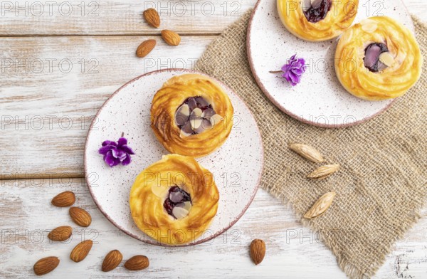 Small cheesecakes with jam and almonds with cup of coffee on a white wooden background and linen textile. top view, flat lay, close up