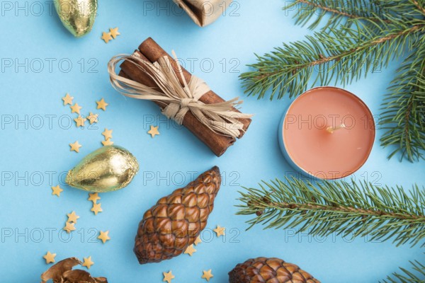 Christmas or New Year composition. Decorations, box, cinnamon, cones, fir and spruce branches, on a blue paper background. Top view, close up, flat lay