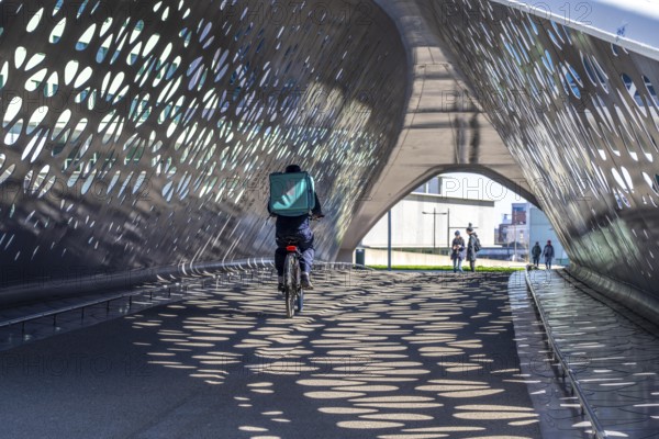 Light effects from the sun in the Parkbruk, a cycle and pedestrian bridge in the city centre of Antwerp, spanning a multi-lane city centre road with tram lines, and thus connecting two lively city districts Kop Spoor Noord and Eilandje, Belgium, without any crossings, Europe