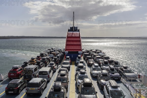 Ferry loaded with cars, sun reflected on the sea, bright sky in the background, Rosslare Harbour Ferry