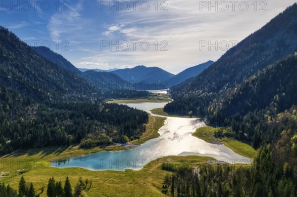 A quiet valley with a lake, surrounded by wooded mountains under a sunny sky, Mittersee