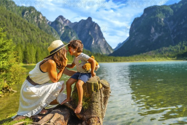 Mother and son sharing a tender moment while enjoying the breathtaking scenery of lake dobbiaco in the italian dolomites during their summer vacation