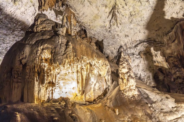 Large stalactites and stalagmites creating geological formations inside postojna cave, a famous tourist attraction in slovenia