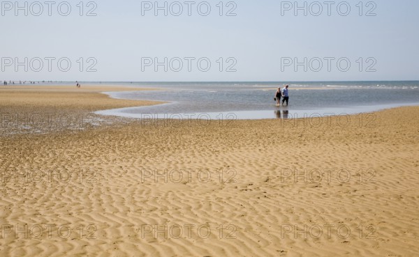 A couple paddling in shallow water by wide sand beach at Hunstanton, north Norfolk coast, England, United Kingdom, Europe