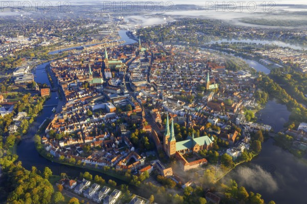 Aerial view over the river Trave and old town and churches of the Hanseatic City of Lübeck in the fog in autumn, fall, Schleswig-Holstein, Germany, Europe