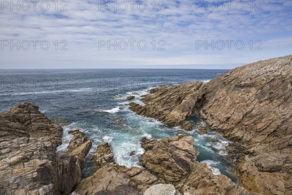 Rocky west coast of the Quiberon peninsula in Brittany, France, with a partly cloudy sky. Crashing waves and rocks, Europe