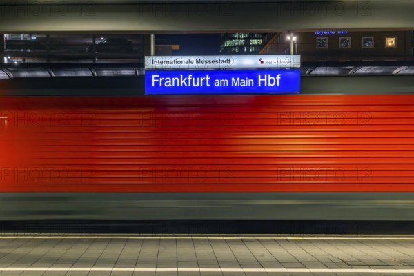 Central station in the evening. Station sign with passing train. Motion blur. Frankfurt am Main, Hesse, Germany, Europe