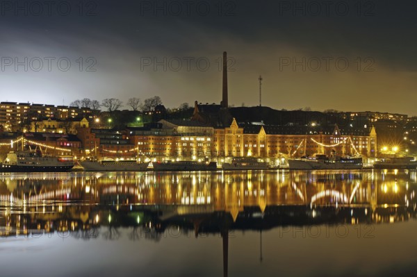 Night view with illuminated waterfront buildings and reflections in the water, winter, ice, capital city, Södermalm, Stockholm, Sweden, Europe
