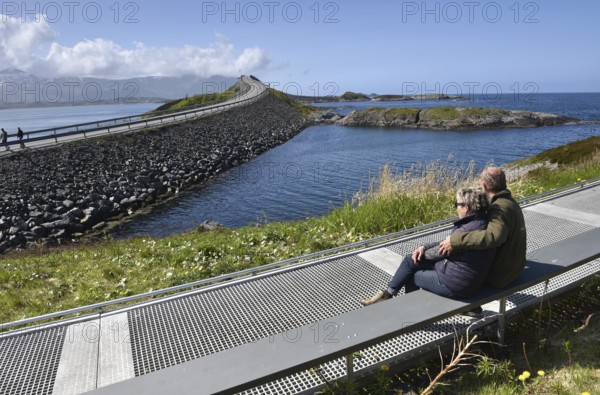 Couple sitting on a bench on the Atlantic Road in Norway