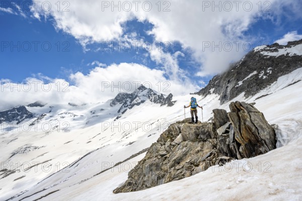 Mountaineer on a rock between snow, descent from the summit of Schönbichler Horn, view of snow-covered and glaciated mountain landscape with summit Großer Möseler, Berliner Höhenweg, Zillertal Alps, Tyrol, Austria, Europe